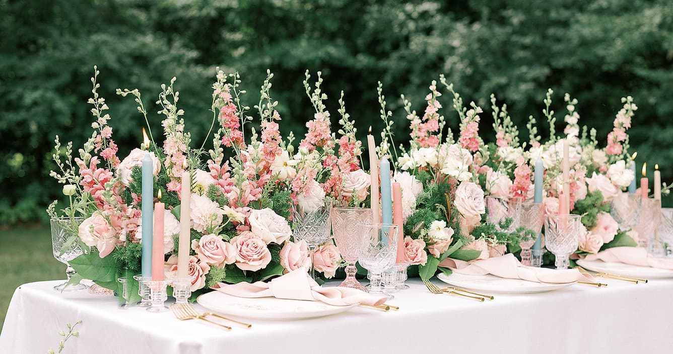 elegant floral table arrangement with pink roses, white candles, and crystal glassware